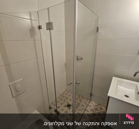 מקלחון זכוכית עם רצפת אריחים ודלתות מתכת